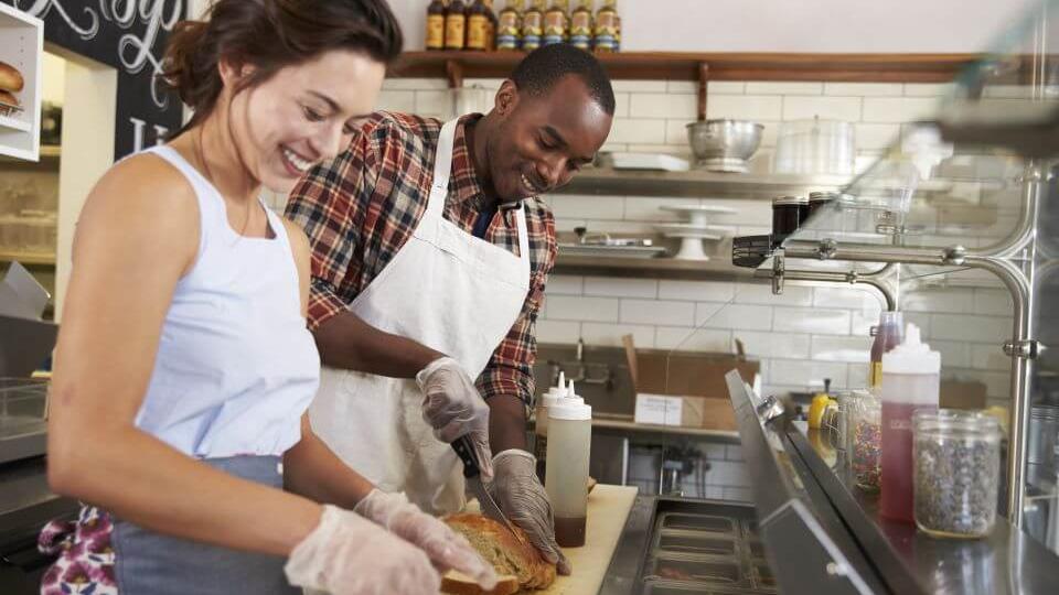 A man and a woman preparing a sandwich 